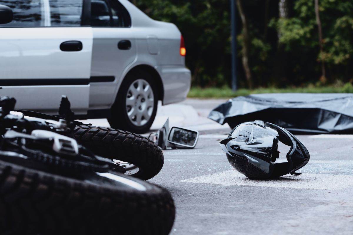 A motorcycle and helmet lay in the street after an accident.