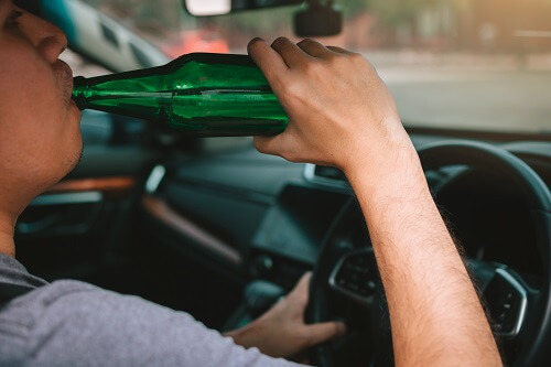 A man is drinking behind the wheel. This is not a way to prevent drunk driving accidents.