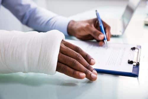 A person with an arm injury signs forms.