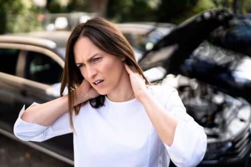 A woman holds her neck after a whiplash injury in a car accident.