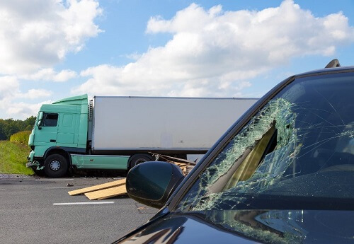 One of the many truck accidents that happen each year in North Carolina. A crashed semi is pictured next to a car with a busted windshield.
