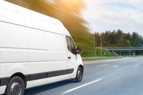 A white cargo van drives down a North Carolina highway.