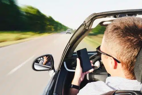 Closeup of a distracted man using his cellphone while driving.