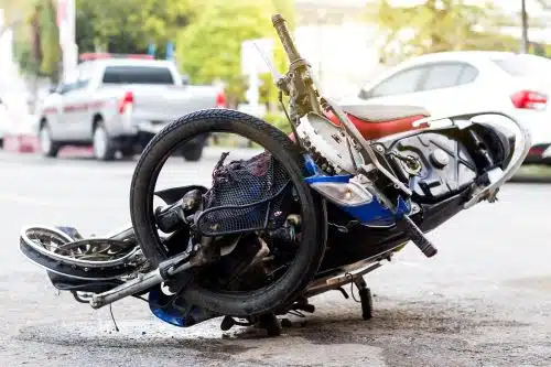 A mangled motorcycle lies in the middle of the road after an accident.