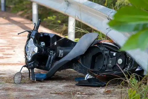 A motorcycle lies broken under a guard rail after an accident.