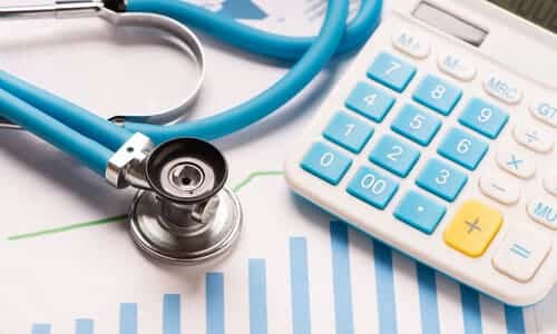 A stethoscope and a calculator resting on top of a patient's chart.