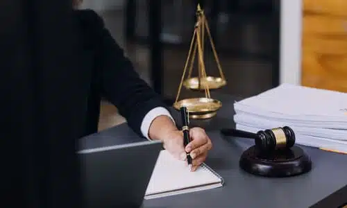 A lawyer in an office taking notes for a client's insurance claim.